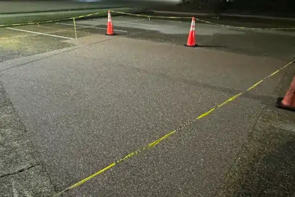 Construction area marked with traffic cones and caution tape on a dark surface.